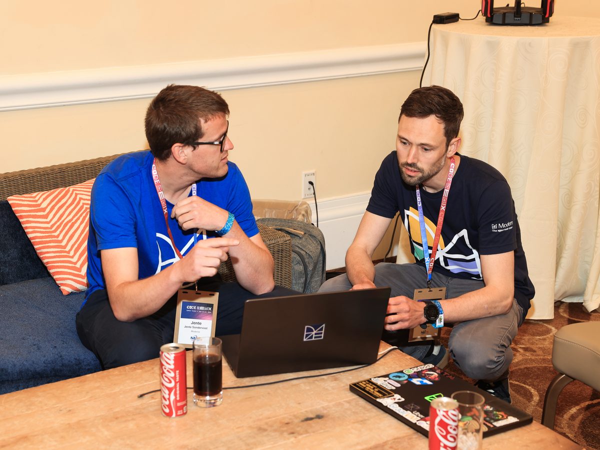 Two attendees pairing over laptops at a Hack Track table