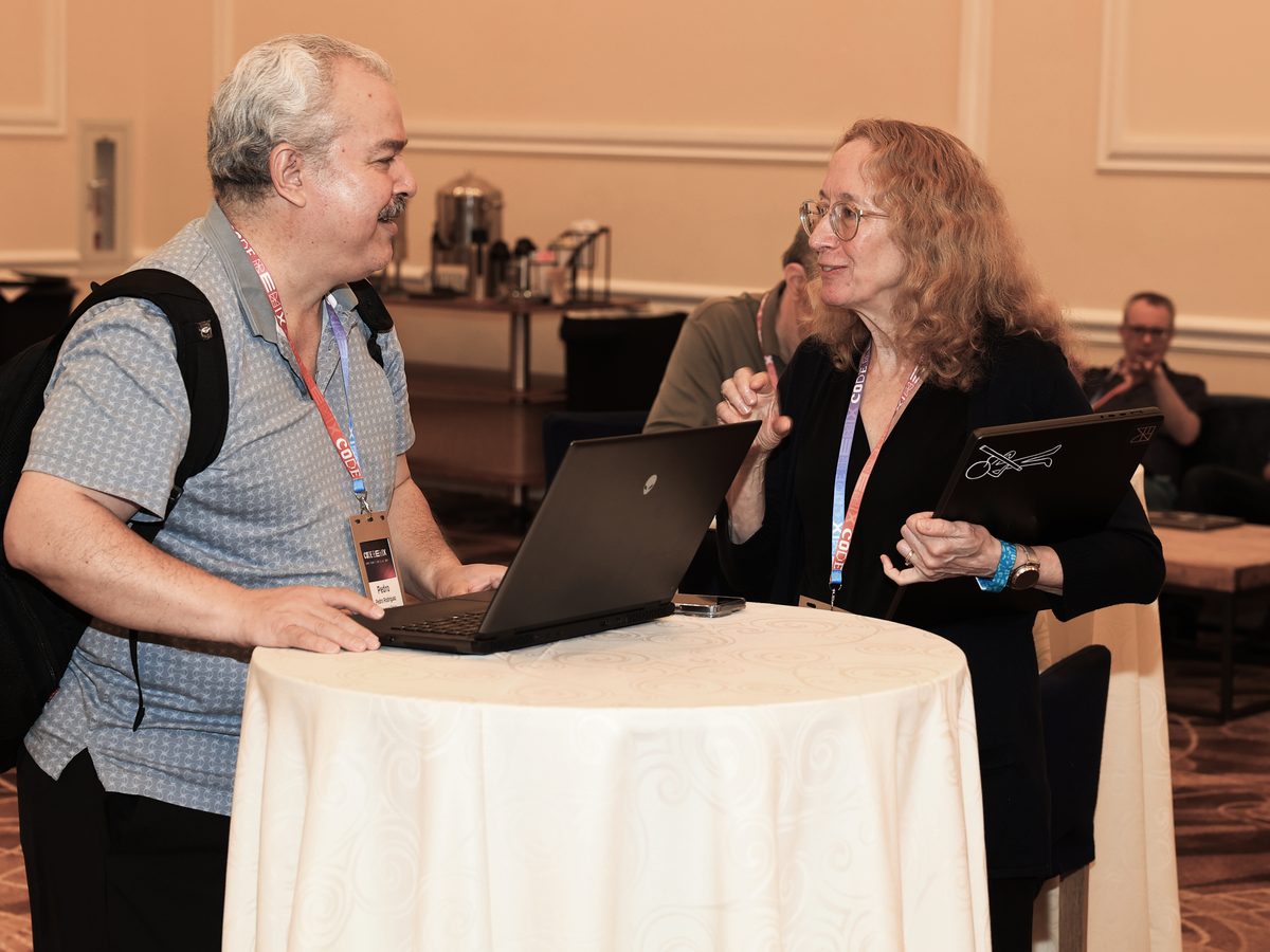 Two attendees talking through a problem at a standing table